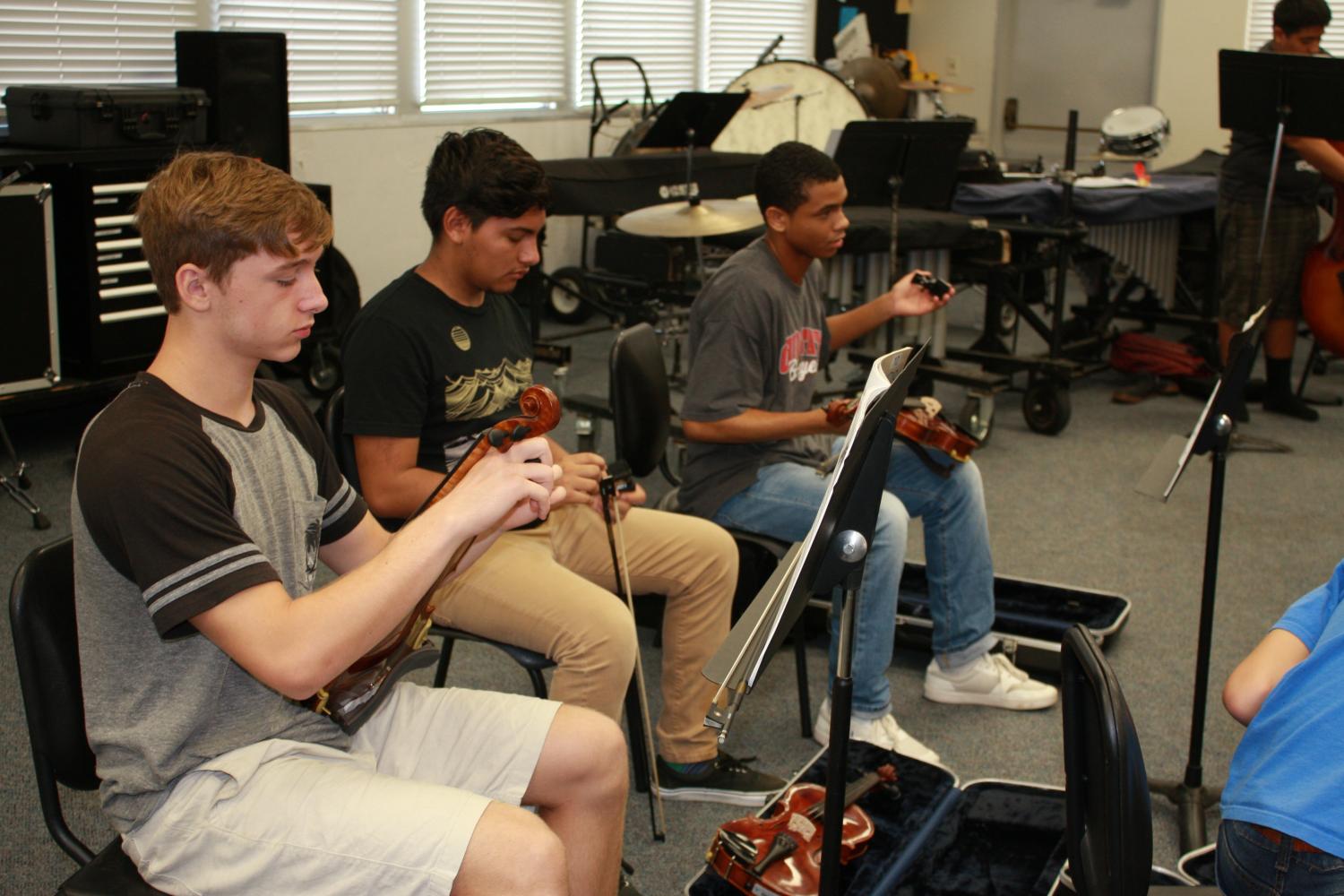 Students (left to right) Kaleb Hillan, Frederick Bavinez, and Chris Green warm up for the new strings class.