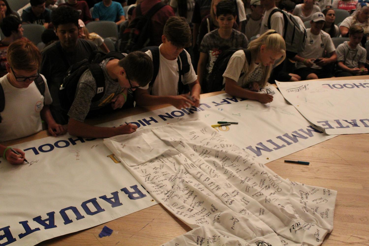 Students sign gown representing their commitment to graduation