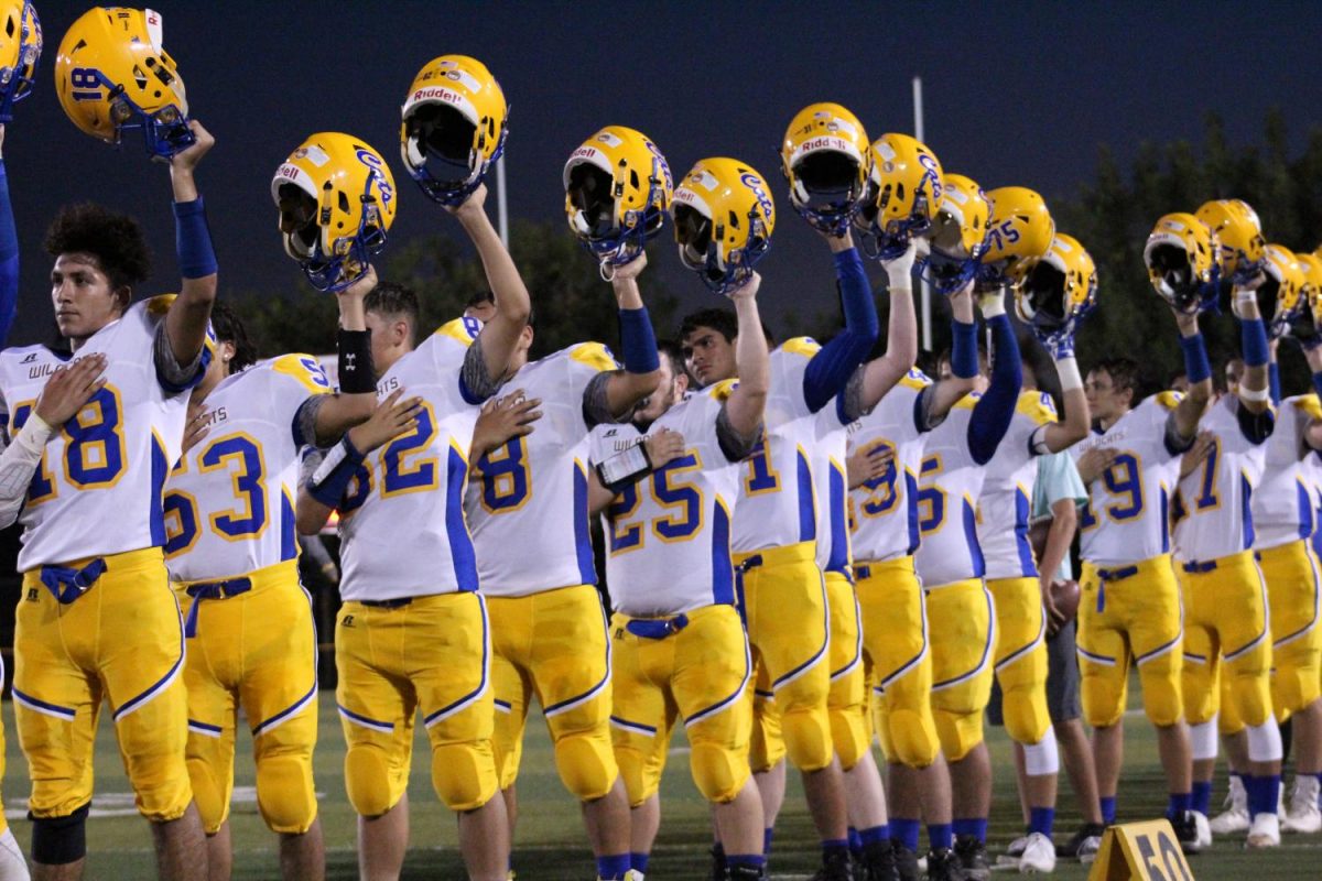 Taft High Varsity Football team raising their helmets during the end of the National Anthem.