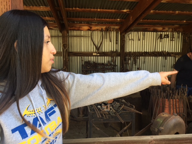 Oil Tech Sophomore Yasmin Cisneros pointing to one of the blacksmith tools while she described the display.