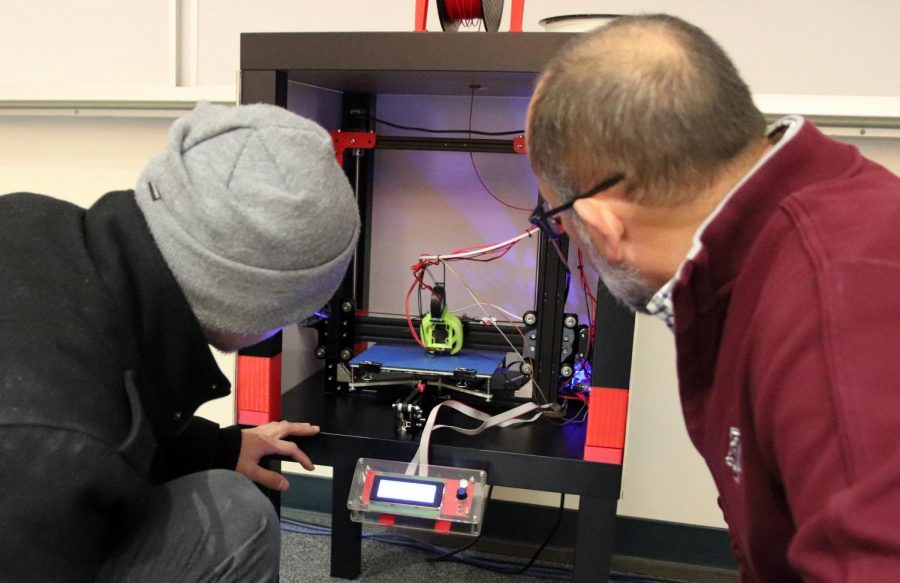 Eduardo Morales showing Ted Pendergrass how his 3-D printer works.