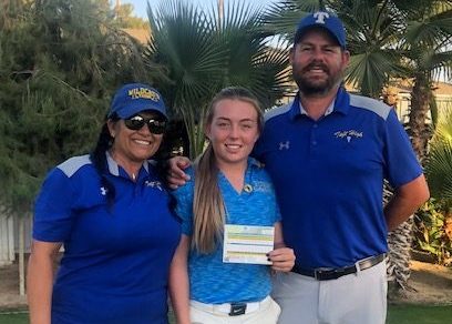 Macayla Wells shows off her scorecard with coaches Charlotte Kidd and Mike Cowan.